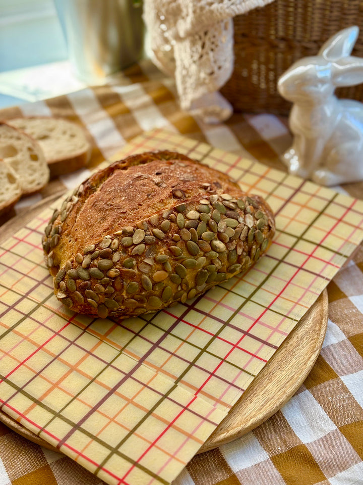 Eco-friendly reusable beeswax bread bag holding a fresh artisan sourdough loaf, made from organic cotton and natural beeswax—perfect for plastic-free, sustainable sourdough bread storage