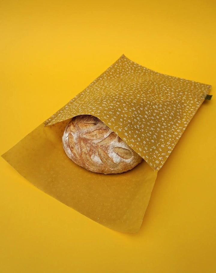 Eco-friendly reusable beeswax bread bag holding a fresh artisan sourdough loaf, made from organic cotton and natural beeswax—perfect for plastic-free, sustainable sourdough bread storage
